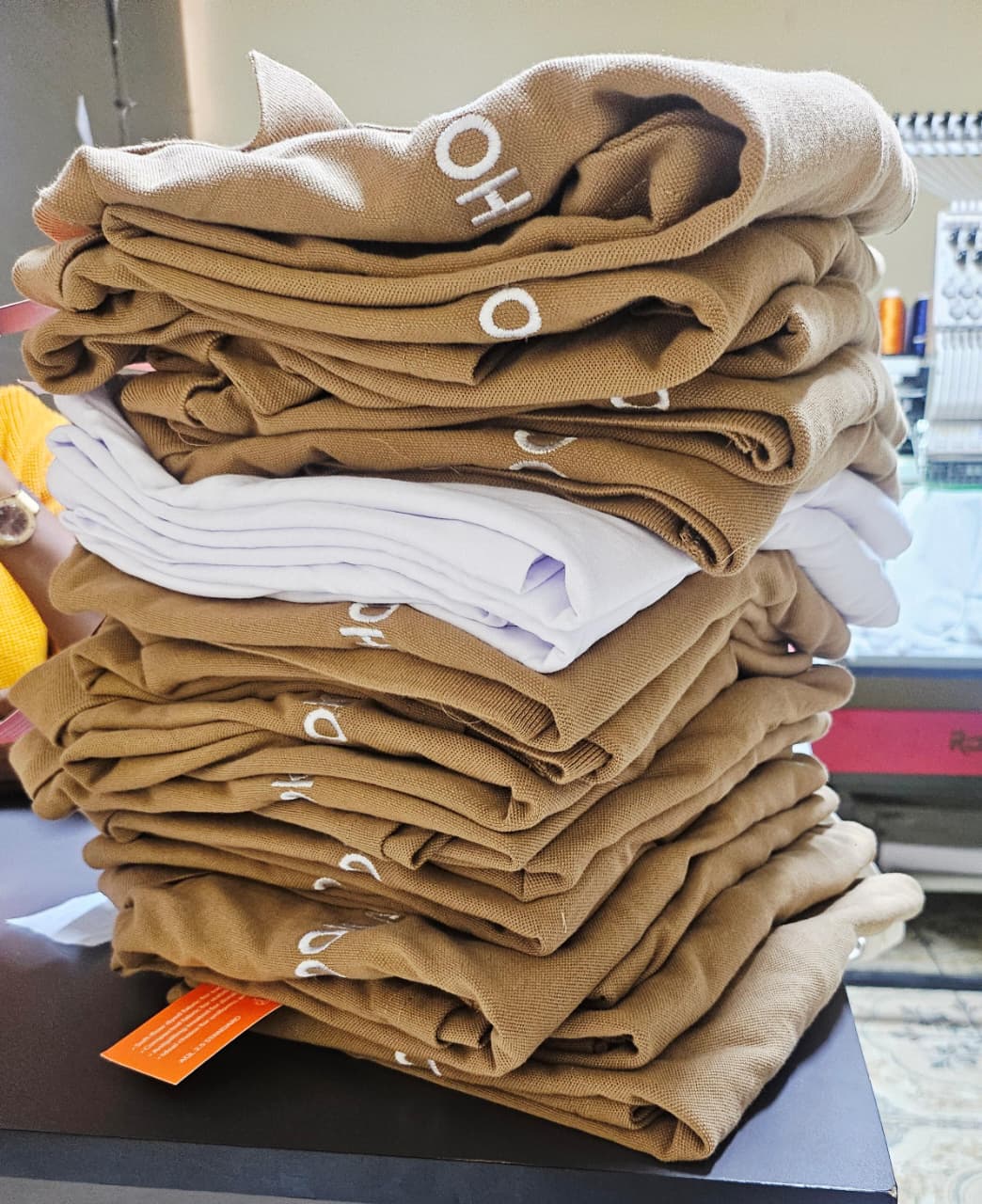 Folded stack of tan embroidered corporate polo shirts